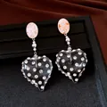 Dettaglio di orecchini a cuore in resina vintage con strass su vassoio nero. - Stile Cuore (HE33928) / Bianco