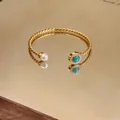 Detail view of 18K gold plated twisted cable cuff bracelet with pearl and turquoise. - Gold Plated Twisted Cable Style / Gold