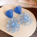 Close-up detail of blue resin triangle stud earrings with translucent flower pendants - Silver Post Flower Pendant Style / Blue