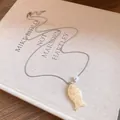 Vue détaillée d'un pendentif en forme de poisson en résine sur une chaîne fine - Poche zippée