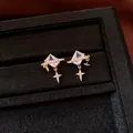 Vue macro détaillée de boucles d'oreilles vintage dorées avec pierre carrée et breloque étoile - Or