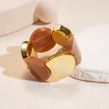 Close-up of acrylic and gold-toned circular panels on a retro elastic bracelet. - Gold-Grey Coffee