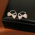 Detailed macro shot of elegant silver bow zircon clip-on earrings on a black jewelry box - Bow / Silver