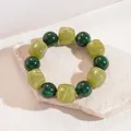 Close-up detail of vintage green marbled acrylic beaded elastic bracelet on a stone platform - Green