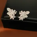 Close-up detail of sparkling cubic zirconia floral ear clips displayed on a black leather box - Flower Leaf / Silver