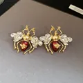 Elegant vintage bee earrings with red enamel and clear crystals on a grey background. - Earrings (Silver Earring Post) / Gold-Red
