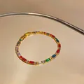 Detailansicht eines Goldarmbandes mit bunten rechteckigen Edelsteinen auf einem Spiegeltisch - Gold Mehrfarbig Stil (HB5696)
