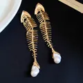 Close-up of vintage gold fish bone necklace with pearl and rhinestone details - Earrings / Gold