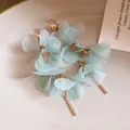 Detail shot of mint green mesh flower earrings with elegant gold bar tassels on plate - Clip-on Earrings / Green