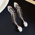 Macro detail of high-end vintage silver fishbone pendant featuring large pearl accent - Earrings / Silver