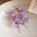 Detail of purple mesh flower earrings with gold bar tassels displayed on a white plate - Clip-on Earrings / Purple