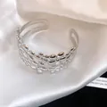 Close-up detail view of elegant silver floral metal cuff bracelet on white silk background - Double Layer Flower / Silver