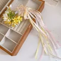 Detailed close-up of a ballet style hair clip with mesh flower and long pastel ribbons - Yellow