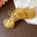 Elegante pinza para el pelo con lazo de organza dorada, bordes rizados y detalle de corazón - Clip Giratorio / Amarillo