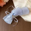 Detalle de un pasador de lazo de encaje azul claro con una estrella de cristal brillante - Clip Giratorio / Azul