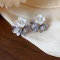 Close-up of delicate flower stud earrings with white and purple petals and zircon centers. - Triple Flower Cluster Style / Blue