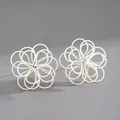 Vista detallada de pendientes de flores huecas pintados de blanco con diseño entrelazado - Beige