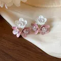 Detailed macro view of elegant pink and white enamel flower earrings with zircon centers. - Triple Flower Cluster Style / Pink