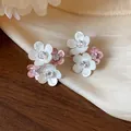 Close-up of elegant floral stud earrings with white and pink petals and zircon center - Hammered Texture Flower Style / Pink