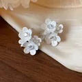 Macro detail of elegant white flower stud earrings featuring sparkling zircon centers - Multi-Layered Petal Style / White