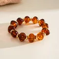 Vintage amber-colored oval acrylic beaded bracelet with gold-tone spacers detail view - Brown