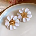 Primo piano di eleganti orecchini a lobo a fiore in smalto bianco su piatto - Bianco