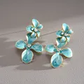 Détail macro des boucles d'oreilles fleurs en émail bleu avec de brillants strass - Style Fleur à Double Couche (HE34061) / Bleu