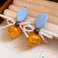 Detailed view of vintage-style wood and yellow resin earrings featuring a white pearl bow - Vintage Bowknot Style / 925 Silver Pin - Blue & Yellow