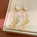 Close-up view of elegant gold starfish and shell dangle earrings with pearls for vacation - Gold-Pink Hook Style