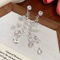 Detailed view of silver needle earrings with shimmering glass water drop tassels - Silver Earring Post-White