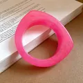 Close-up of a pink marbled resin geometric bangle with irregular curved design - Rose Red