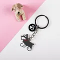 Close-up of a cute enamel Schnauzer dog keychain with a paw print charm on a pink background - Grey Schnauzer with Paw Print Tag
