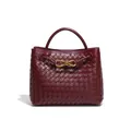 Elegante borsa tote bordeaux tessuta a mano con una chiusura decorativa a fiocco dorato. - Borgogna