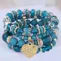 Close-up detail of teal Bohemian layered beaded bracelets featuring a gold heart charm - Lake Blue