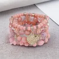 Close-up of pink Bohemian beaded bracelet set with engraved gold heart pendant - Warm Tone