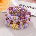 Close-up of bohemian purple beaded bracelet with engraved gold heart charm - Light Purple