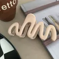 Close-up detail of a matte wavy hair claw clip in elegant nude beige for hair styling - Apricot