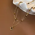 Gelaagde gouden ketting met tijgeroog kralen en zonnehanger op bruine achtergrond - Maillard Tijgeroog Zonnebloem Ketting