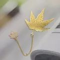 Detailed macro view of a delicate gold brass maple leaf bookmark with hollow veins and chain. - Maple Leaf