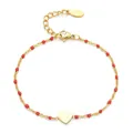 Primer plano de pulsera de acero dorado con cuentas rojas y un dije de corazón - Rojo