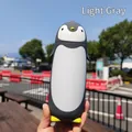 Creative light grey penguin-shaped cartoon glass water bottle shown in a hand outdoors - 300ml / Gray