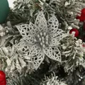 Detailaufnahme einer silbernen Glitzer-Weihnachtssternblume auf verschneitem Zweig - Silber