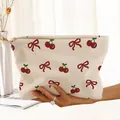 Close-up detail of the corduroy makeup pouch featuring red bow and cherry prints. - Beige Cherry Bow (CM189336)