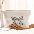 Close-up of white corduroy cosmetic bag with black lace bow print and zipper - White Black Mesh Bow (WB210960)