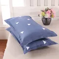Set of two modern blue pillowcases with white triangle patterns shown on a cozy bed - Love Nest Gray