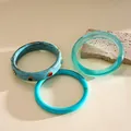 Vue détaillée de bracelets en résine marbrée et translucide sur un support en pierre - Bleu