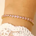 Macro view of a gold-tone tennis bracelet featuring sparkling pink round-cut stones - 14k Gold Pink Zirconia (0450)