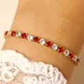 Close-up detail of a gold tennis bracelet with alternating red and white sparkling gems - 14k Gold Red & White Zirconia (3071)