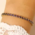 Close-up of elegant gold-tone tennis bracelet with oval purple crystals on a woman's wrist. - 14k Gold Purple Zirconia (5920)