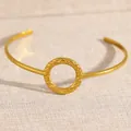 Elegant gold-colored open cuff bracelet featuring a textured circular centerpiece - Hammered Ring Style (2027)